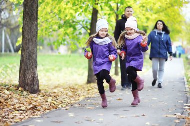 Sonbahar parkında yürüyüşe çıkmış çocuklar. Yaprak parkta düşer. - Aile. Düş! Mutluluk.