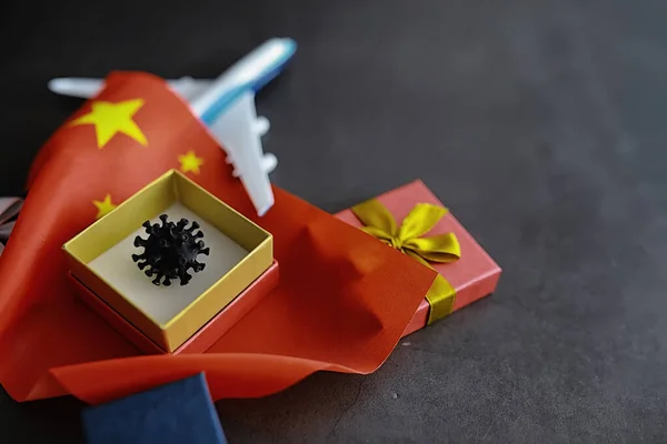 The concept of the world coronavirus pandemic. The geographical location of the virus. China flag and virus model and gift box.