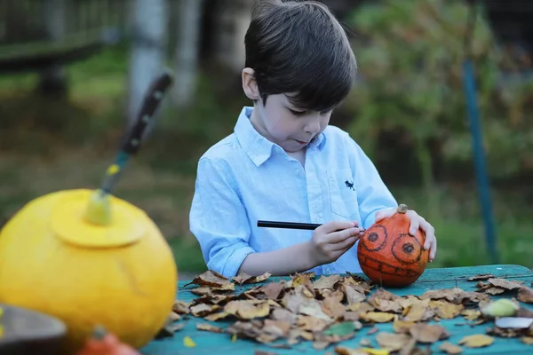 Autumn traditions and preparations for the holiday Halloween. A house in nature, a lamp made of pumpkins is cut out at the table.