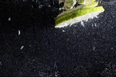 Olgun tatlı limonun üzerine su damlıyor. Metnin için kopyalama alanı olan taze kireç arkaplanı. Vejetaryen ve vejetaryen kavramı.