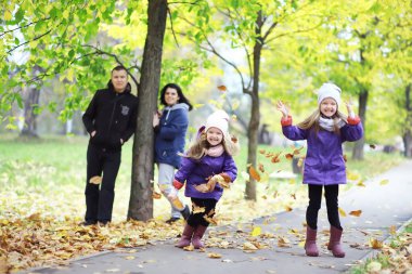 Sonbahar parkında yürüyüşe çıkmış çocuklar. Yaprak parkta düşer. - Aile. Düş! Mutluluk.