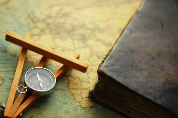 Travel and adventure search concept. Vintage aged map with shabby book and compass. Shabby book and compass on the table.