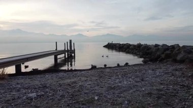 Gün batımında Cenevre Gölü 'nün nefes kesici manzarası, güneş suların ve dağların arasında altın bir yansıma yapıyor. Huzurlu ve resimli bir sahne..