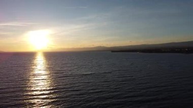 Gün batımında Cenevre Gölü 'nün nefes kesici manzarası, güneş suların ve dağların arasında altın bir yansıma yapıyor. Huzurlu ve resimli bir sahne..