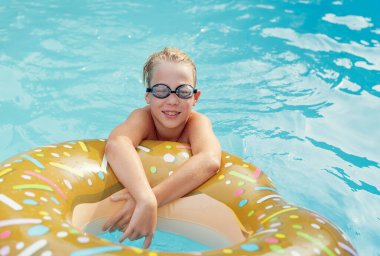 Havuzdaki küçük çocuk. Havuzdaki mutlu çocuklar için yaz ve yüzme aktiviteleri