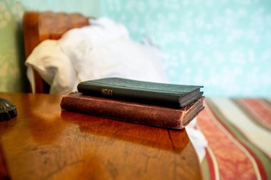 Ahşap başucundaki buruşuk yatak yakınındaki kapalı kitap