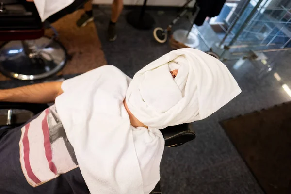 man with a towel on his face. barber's office