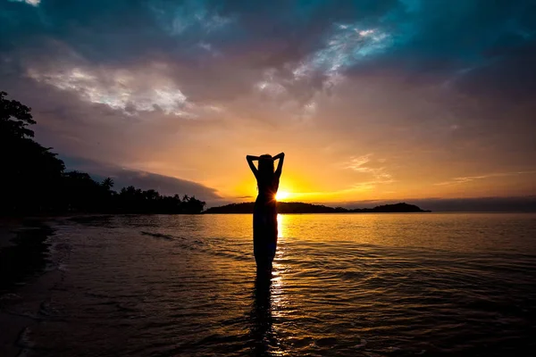 Silhouette sexig tjej i baddräkt liggande och poserar på surfbräda på stranden under solnedgången. Kvinnan vilar efter surfing. Begreppet aktiv livsstil — Stockfoto