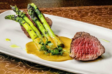 Geleneksel barbekü yaşlı geyik eti backstrap kızartma yeşil kuşkonmaz, havuç ve otlar rustik bir metal levha üzerinde üst görünümü olarak