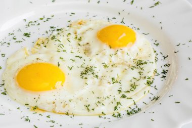 Tuz, biber ve otlarla bir tabakta kızarmış yumurtayı kapatın. iki yumurta
