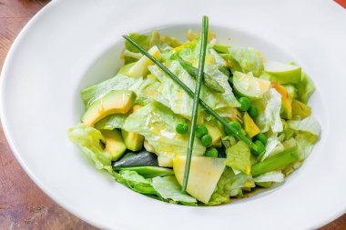 tropikal meyve çiçekleri çeşitli büyük tabak. Vejetaryenler, veganlar ve çiğ gıdacılar için yemek. Beyaz bir tabakta - salata, arugula, elma, bezelye, fasulye, soğan, mango. Makro