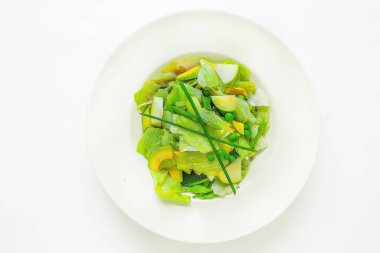 tropikal meyve çiçekleri çeşitli büyük tabak. Vejetaryenler, veganlar ve çiğ gıdacılar için yemek. Beyaz bir tabakta - salata, arugula, elma, bezelye, fasulye, soğan, mango. Yukarıdan görüntüle