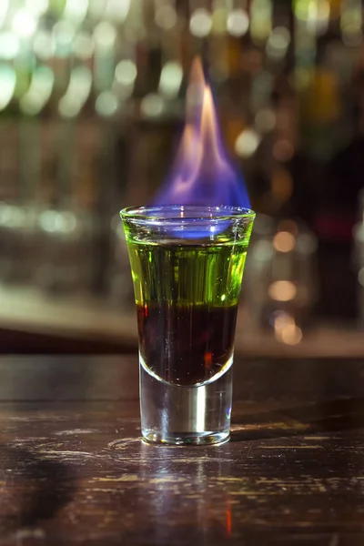 Cóctel de alcohol prendido fuego y quema fondo negro en un vaso pequeño — Foto de Stock