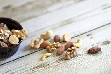 Antika ahşap masadaki kahverengi kokotta karışık fındık.