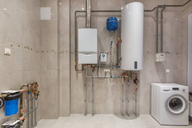 Duvar kazan dairesinde gaz kazanı ve elektrikli su ısıtıcı asılı