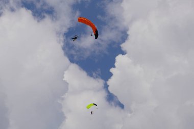  Skydivers bulutların arka planına karşı mavi gökyüzünde uçuyor. Güneşli bir günde gökyüzünde Tandem paraşütçüler                             