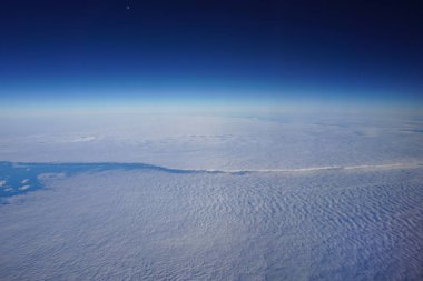 Uçak penceresinden görüntüleyin. Bulutların üzerinde yüksek gökyüzü. Mavi atmosfer arka planı.