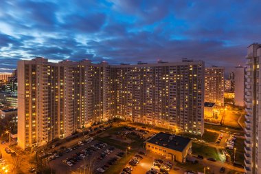 Bir konut çok katlı apartmanın üst görünümü. Pitoresk gün batımı. Gece şehrinin ışıkları