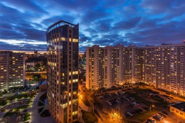 Bir konut çok katlı apartmanın üst görünümü. Pitoresk gün batımı. Gece şehrinin ışıkları