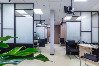 Cam panelleri, ofis mobilyaları ve dijital ekranları olan modern kabin ofisi.