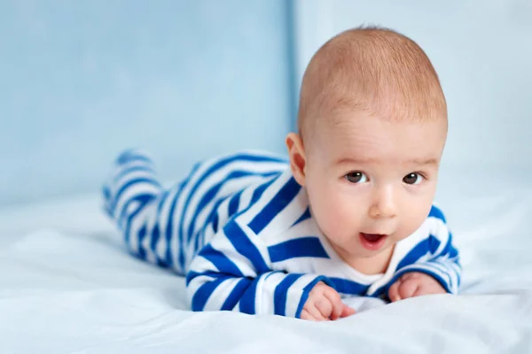 快乐的小男孩躺在床上 有趣的是 四个月大的宝宝穿着条纹睡衣在家里 — 图库照片
