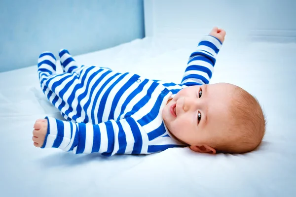 快乐的小男孩躺在床上 可爱的四个月大的婴儿在条纹睡衣在家里 — 图库照片