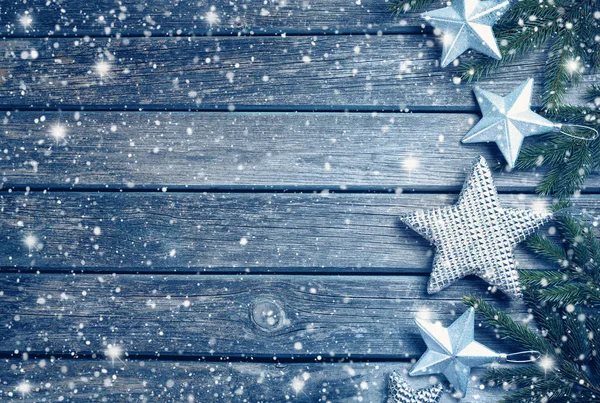 Christmas stars on wooden background with fir tree branches