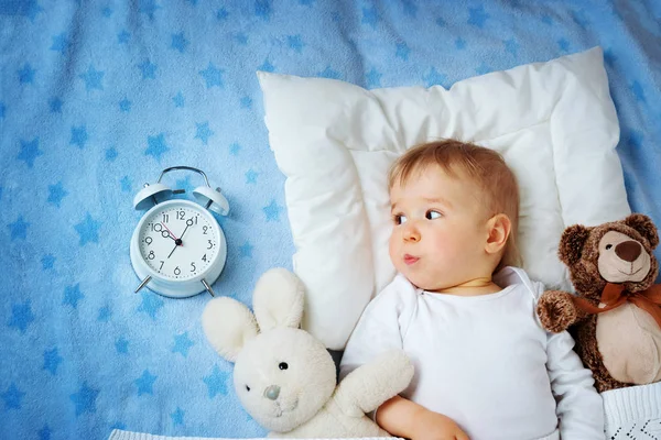 一岁的婴儿躺在床上与闹钟 — 图库照片