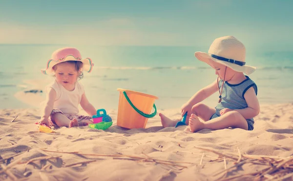 Babygirl en babyboy zittend op het strand — Stockfoto