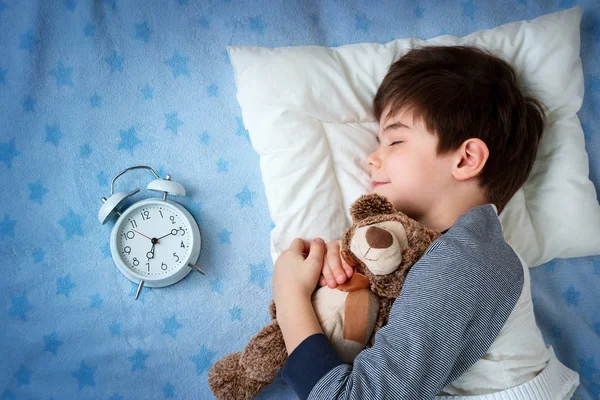 Sechsjähriges Kind schläft mit Wecker im Bett — Stockfoto