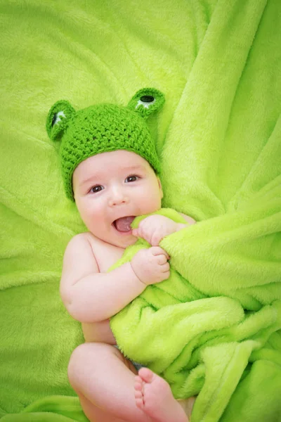 针织的青蛙帽子上柔软的毛毯 绿色背景上的小宝贝 — 图库照片