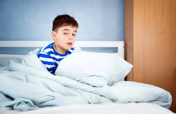 ベッドに座っている眠い少年 疲れた子供の寝室で — ストック写真