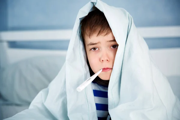 病気の少年がベッドに横たわっています 発熱毛布に包まれた悲しい子 — ストック写真