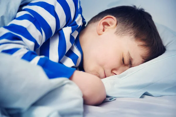 パジャマ姿でベッドで寝ている少年 夜のベッドで枕に横になっている子 — ストック写真