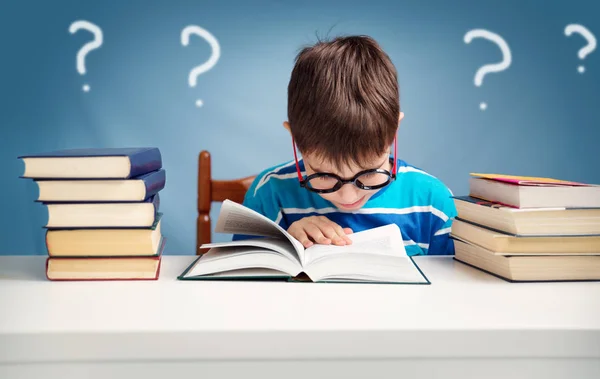 歳の子が家で本を読みます 青色の背景のテーブルに少年の勉強 — ストック写真