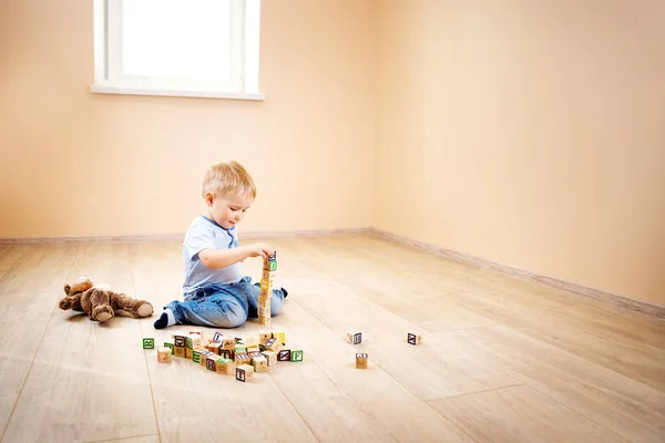 2歳の子供が床に座っていました かわいいです男の子Palyingとともに木製のキューブに家 — ストック写真