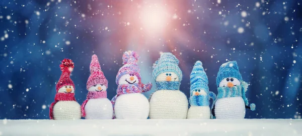 Mavi arka plan üzerinde yumuşak karda küçük snowmans — Stok fotoğraf