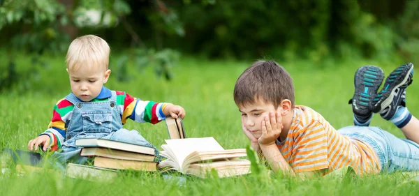 Yedi Yaşında Bir Çocuk Çimlerin Üzerinde Uzanmış Kitap Okuyor — Stok fotoğraf