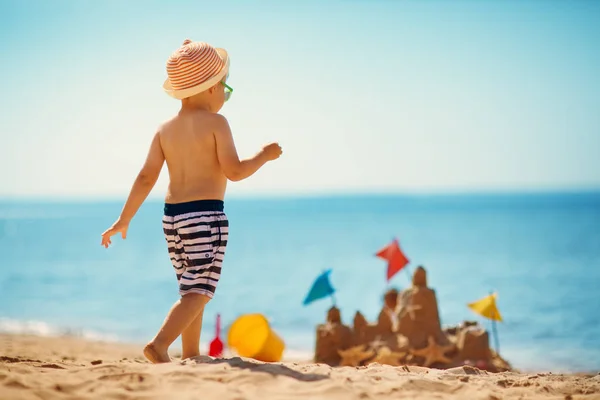 Jongen vergadering glimlachend op het strand — Stockfoto