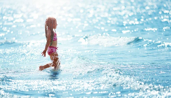 女孩在水里走在沙滩上 — 图库照片