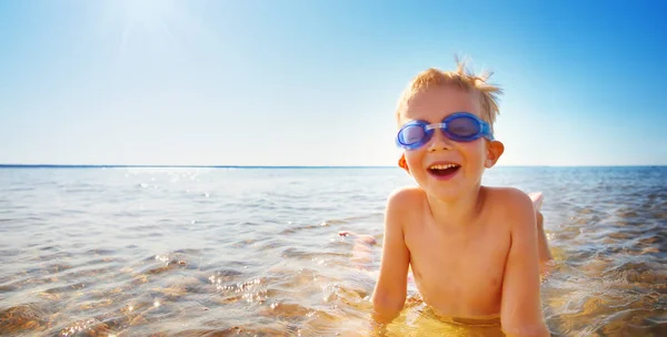 Čtyřletý chlapec hrající na pláž s sklenicemi na koupání — Stock fotografie