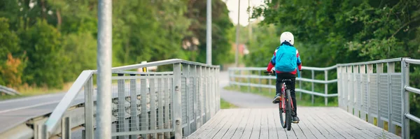 Kind met rugzak rijden op de fiets in het park in de buurt van school — Stockfoto