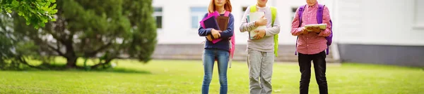 学校の近くの公園に立っているリュックサックを持つ子供たち — ストック写真