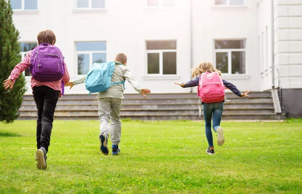 Bambini con zaini in piedi nel parco vicino alla scuola — Foto Stock