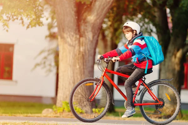 Bambino con zaino in bicicletta nel parco vicino alla scuola — Foto Stock