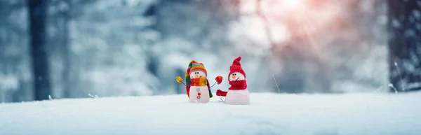 Pequeños muñecos de nieve sobre nieve suave sobre fondo azul —  Fotos de Stock