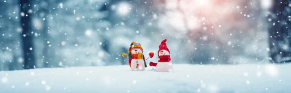 Pequeños muñecos de nieve sobre nieve suave sobre fondo azul —  Fotos de Stock