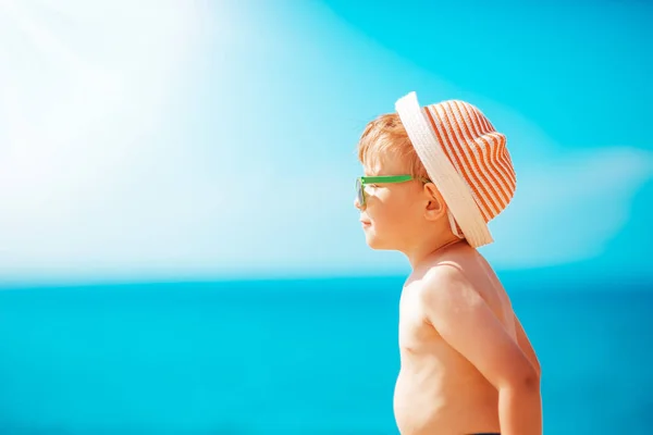 Liten pojke ler mot stranden i hatt med solglasögon — Stockfoto