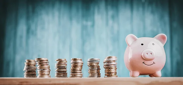 Alcancía con monedas apiladas sobre fondo azul —  Fotos de Stock