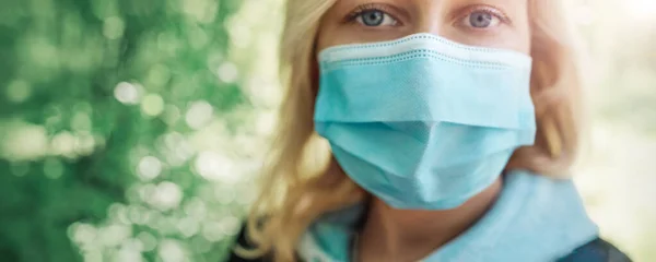 Молода жінка в медичній масці для захисту обличчя на відкритому повітрі в природі — стокове фото